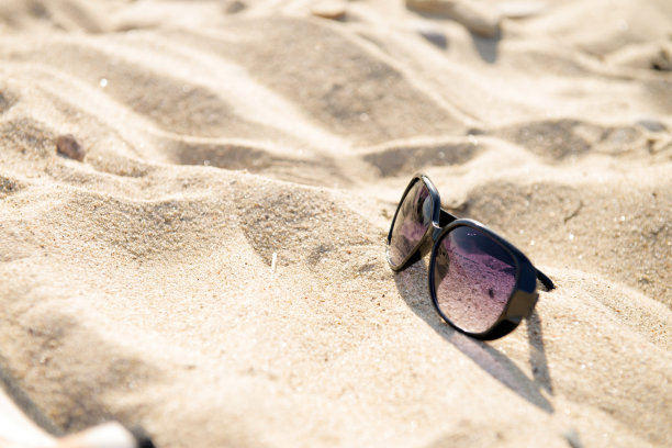 在靠近蓝色的海和沙子的海滩上的太阳镜顶视图。黑色太阳镜的太阳-夏季假日概念图片下载