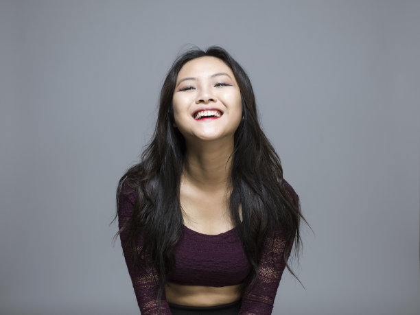 近距离微笑的年轻亚洲女子站在灰色的背景图片下载