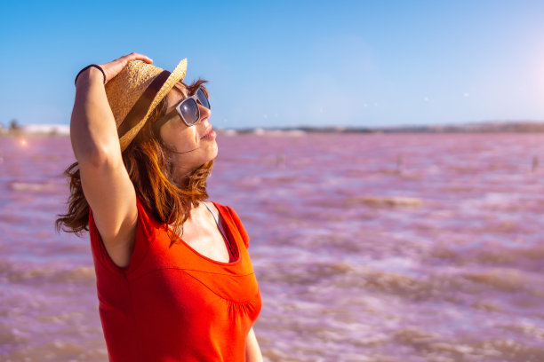 阿利坎特托雷维哈的粉红色泻湖上，女孩穿着红衣服，戴着草帽，享受夏天。瓦伦西亚的社区。西班牙，去地中海度假图片下载