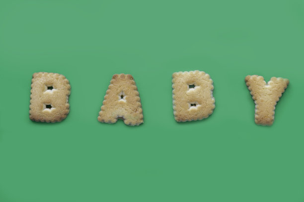 绿色背景上的饼干题词“宝贝”。图片下载