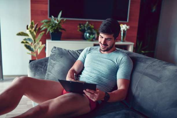 微笑的男性在家只穿着内衣在剪贴板上工作图片下载