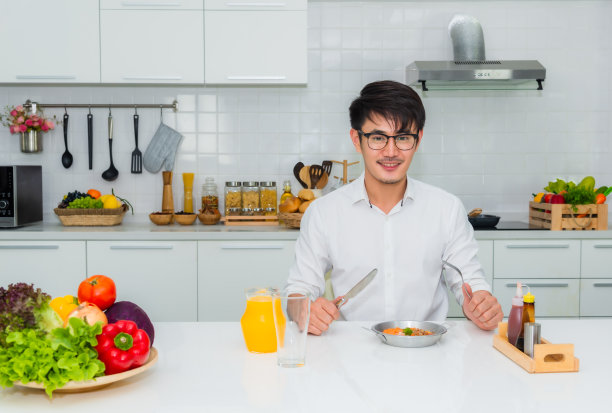亚洲英俊的商人正坐着喝着橙汁吃早餐图片下载