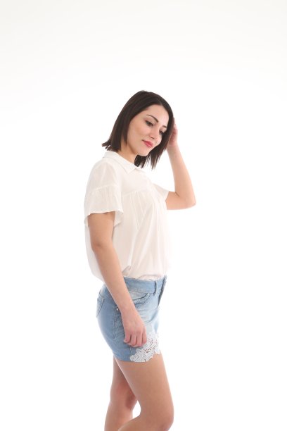 年轻美丽的女人在短裙的牛仔裤前面白色的背景图片下载