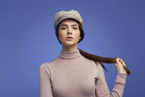 女孩梳着马尾辫，穿着休闲服装，在紫色背景上摆姿势图片下载