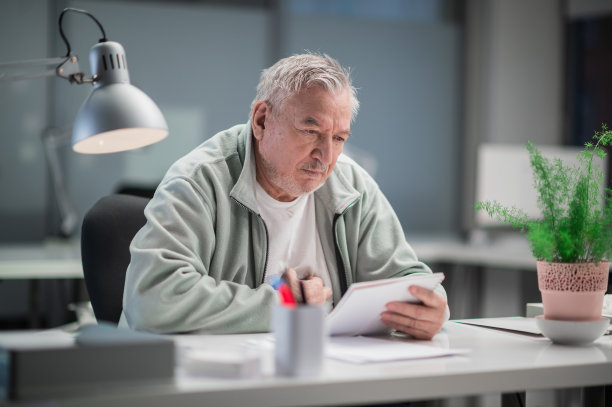 一位白发苍苍的老人在诊所里阅读药品使用说明图片下载