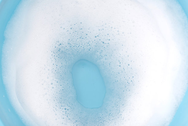 蓝色塑料盆的水面上有泡沫。泡沫作为质地或背景。图片下载