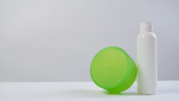 绿色和白色塑料化妆品膏霜或凝胶管和瓶子，孤立在白色背景与苹果图片下载