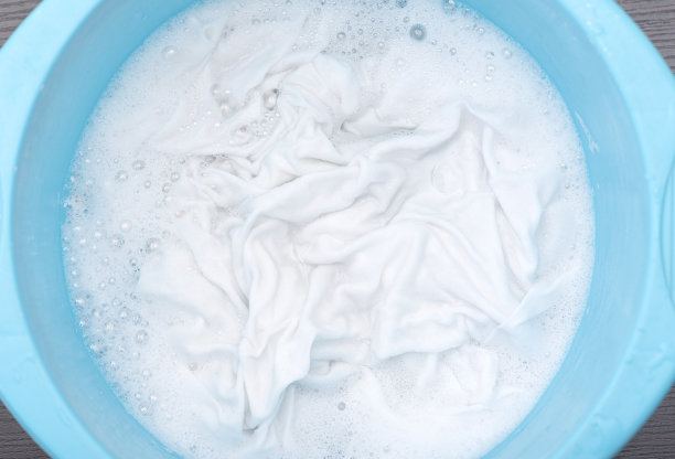 白布，衬衫，t恤浸泡在用泡沫水的蓝色塑料盆里，特写图片下载