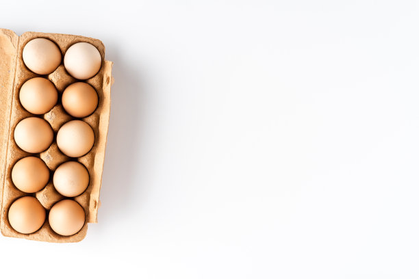 鸡蛋装在盒子里，放在白色的桌子上。俯视图图片下载