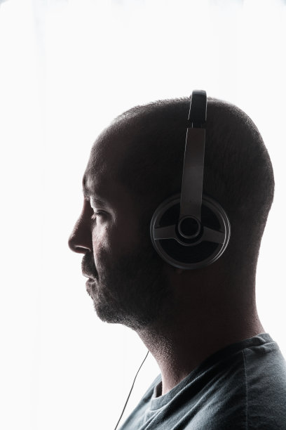 迷人的年轻男子戴着耳机在白色背景下听音乐图片下载