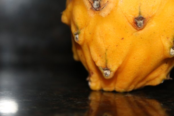 黄色的火龙果(火龙果)和它在黑色大理石台面上的倒影图片下载