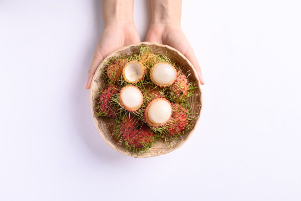 熟透的红毛丹果实在竹篮里被女人的手捧着图片下载