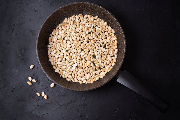 用平底锅烤新鲜花生，背景为黑色。图片下载