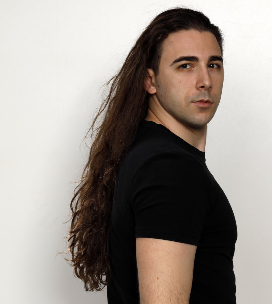 一个长卷发的帅哥在工作室摆造型。图片下载