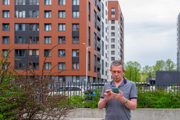 一个成年男子站起来，在智能手机上输入信息图片下载