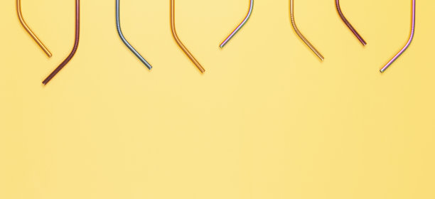 彩色可重复使用的不锈钢吸管在柔和的黄色背景。俯视图，复制空间图片下载
