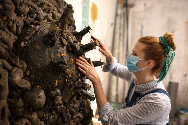 女艺术家在车间里与一个冠状病毒雕塑图片下载