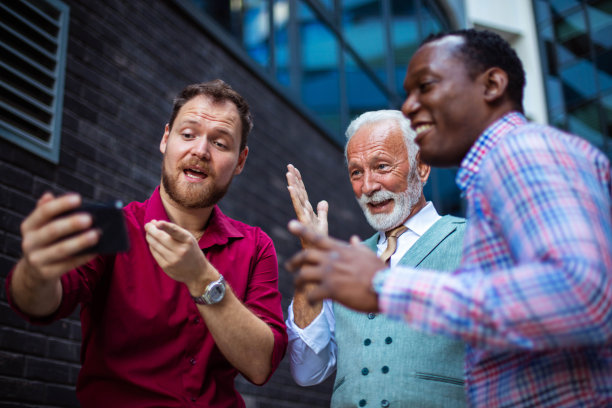 三个商人站在外面使用手机。重点是背景。图片下载