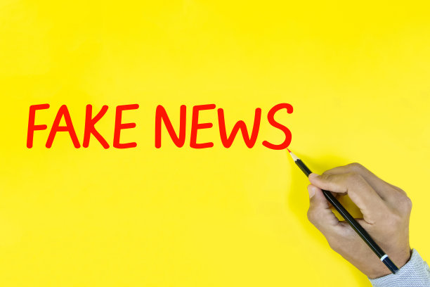 黄色背景上男性手写“假新闻”。图片下载