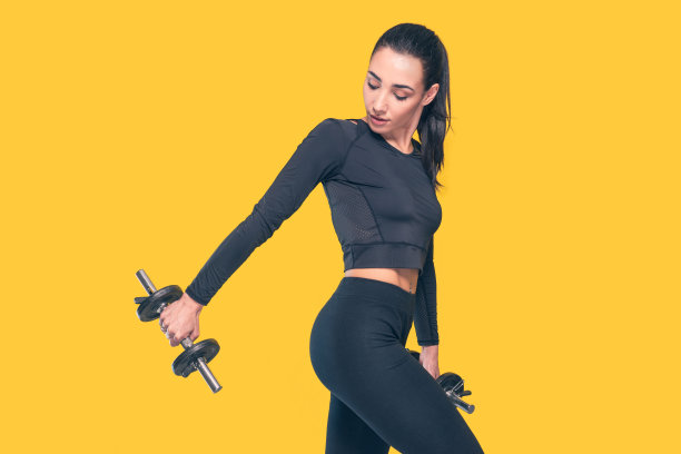 美丽活跃的年轻运动有吸引力的白人运动员运动女子训练在黑色运动装与黄色的背景-工作室拍摄与漂亮苗条的年轻运动黑发模特在体操锻炼摆姿势图片下载
