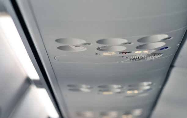 在飞机上系好安全带和禁止吸烟标志，飞机上空调的顶控台上。飞机上的标志。图片下载