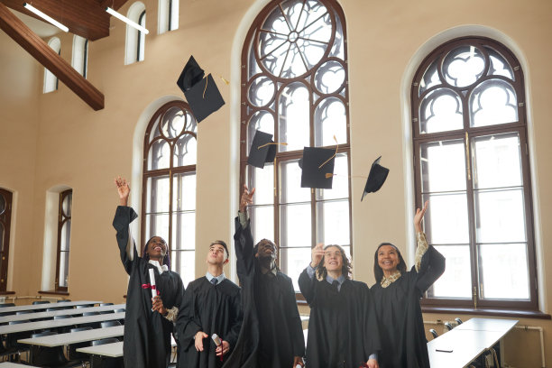 毕业生在室内的空气中抛帽子图片下载
