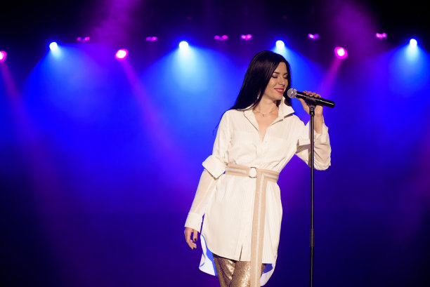 酷歌手与麦克风在明亮的背光舞台上明亮的蓝色灯光图片下载