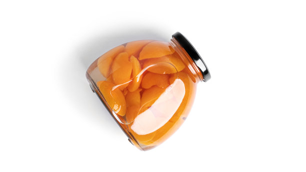 杏罐头装在玻璃罐中。白底上分离出糖浆中的甜杏图片下载