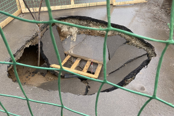 沥青路面的灾难性破坏。帆布上有很深的洞。一个被篱笆围起来的大坑。公路施工技术和人行道施工质量差。摧毁了道路。图片下载