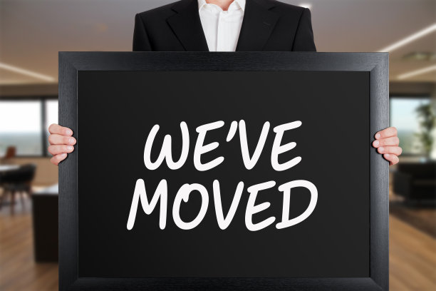 商人拿着一个大招牌，上面写着“我们搬家了”。图片下载