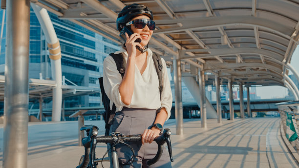 亚洲女商人背包打电话手机聊天微笑在城市街道去办公室工作。体育女用手机工作。图片下载