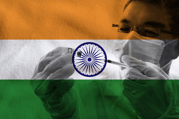 医学研究人员戴着防护口罩和防护手套，手持冠状病毒疫苗玻璃瓶，从药瓶中向印度国旗背景下填充注射器。图片下载