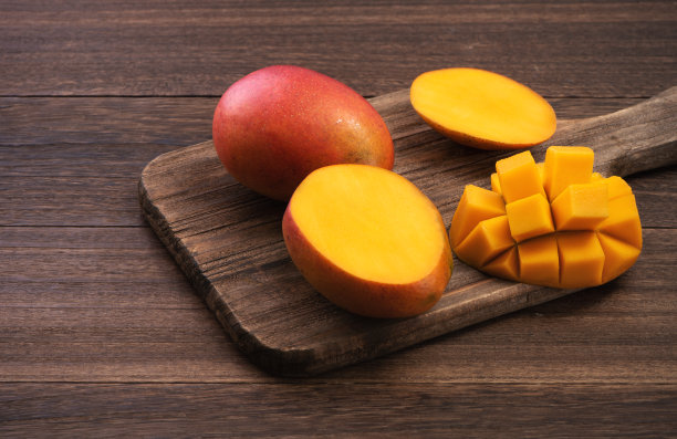 芒果。新鲜的芒果水果和树叶在深色木桌子的背景。图片下载