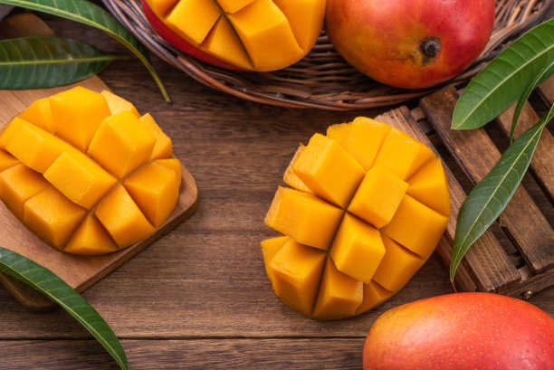 芒果。新鲜的芒果水果和树叶在深色木桌子的背景。图片下载