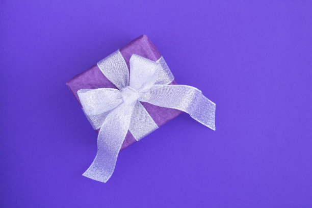 顶视图的礼盒与银色蝴蝶结在紫色的背景图片下载
