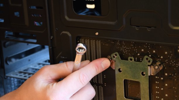 公手用金属扳手将螺母固定在电脑主板上的螺栓上图片下载