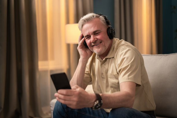 一位精力充沛的老人正在听新的歌单。老年人听广播。一位退休男子戴着耳机听他最喜欢的广播。微笑的人听音乐图片下载