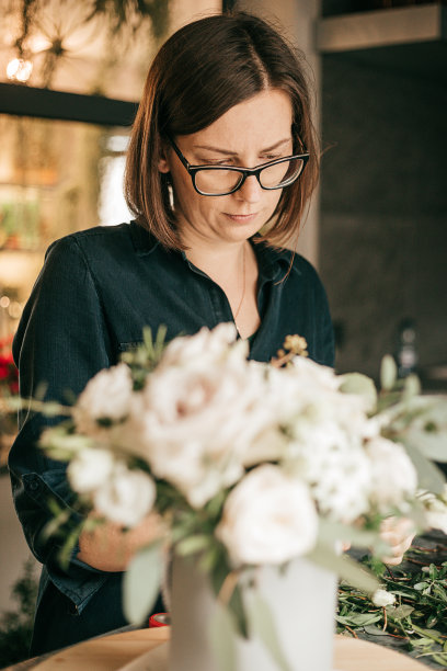 在花店的桌子上，一个卖花的女人正在收集花束。爱好，小型企业理念图片下载