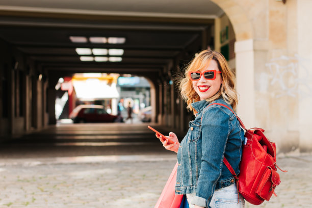美丽的西班牙女人网上购物手机和许多彩色购物袋。夏季销售和生活方式的概念。图片下载