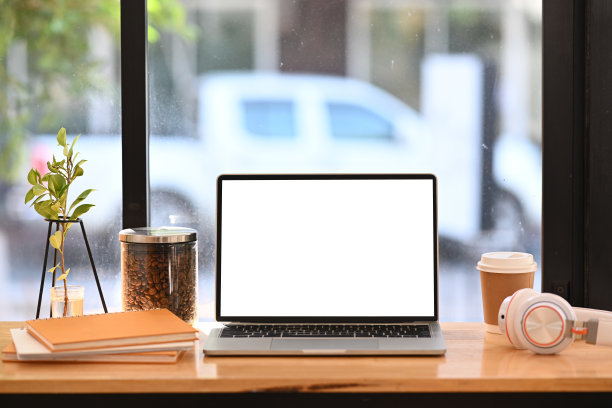 舒适的工作空间，电脑笔记本电脑，耳机，咖啡杯和书在木桌上。图片下载