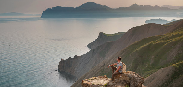 这个年轻人独自在群山的背景下旅行图片下载