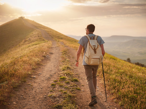 这个年轻人独自在群山的背景下旅行图片下载