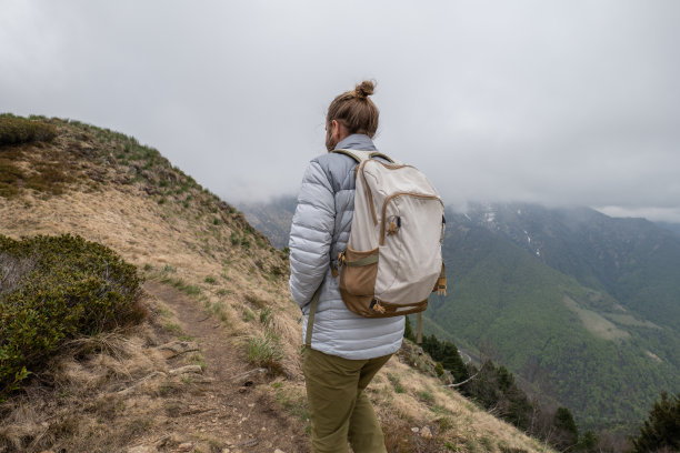 年轻男人在山脊上徒步旅行，阴天图片下载