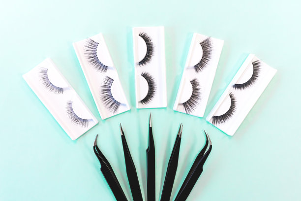 在时尚柔和的薄荷蓝背景下使用不同的睫毛延伸工具。假睫毛和镊子。美丽的概念。妆化妆品。俯视图，平放。布局。图片下载