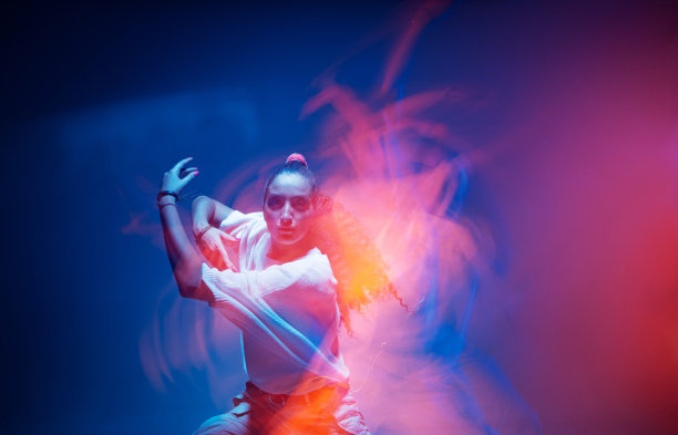 跳舞的混血女孩酷移动在五颜六色的霓虹灯工作室的光。长时间的曝光。火辣辣的现代舞图片下载