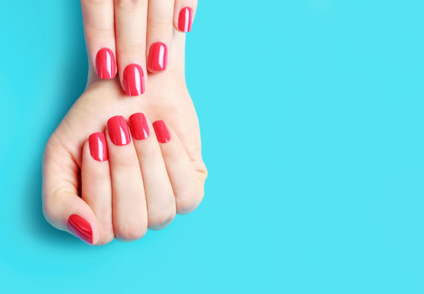 蓝色背景上有红色指甲的女性双手，复制空间图片下载