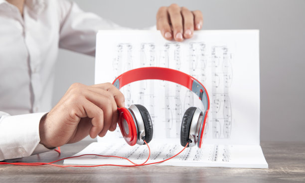 手持耳机的男子在乐谱上标注。图片下载