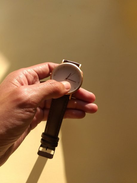 黄色背景下一只手拿着一只手表的照片图片下载