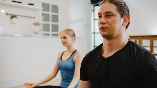 一对年轻的美国夫妇早上穿着运动服在厨房里做瑜伽运动。图片下载