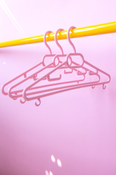 一套三个粉色衣架挂在架子上，以粉色为背景图片下载